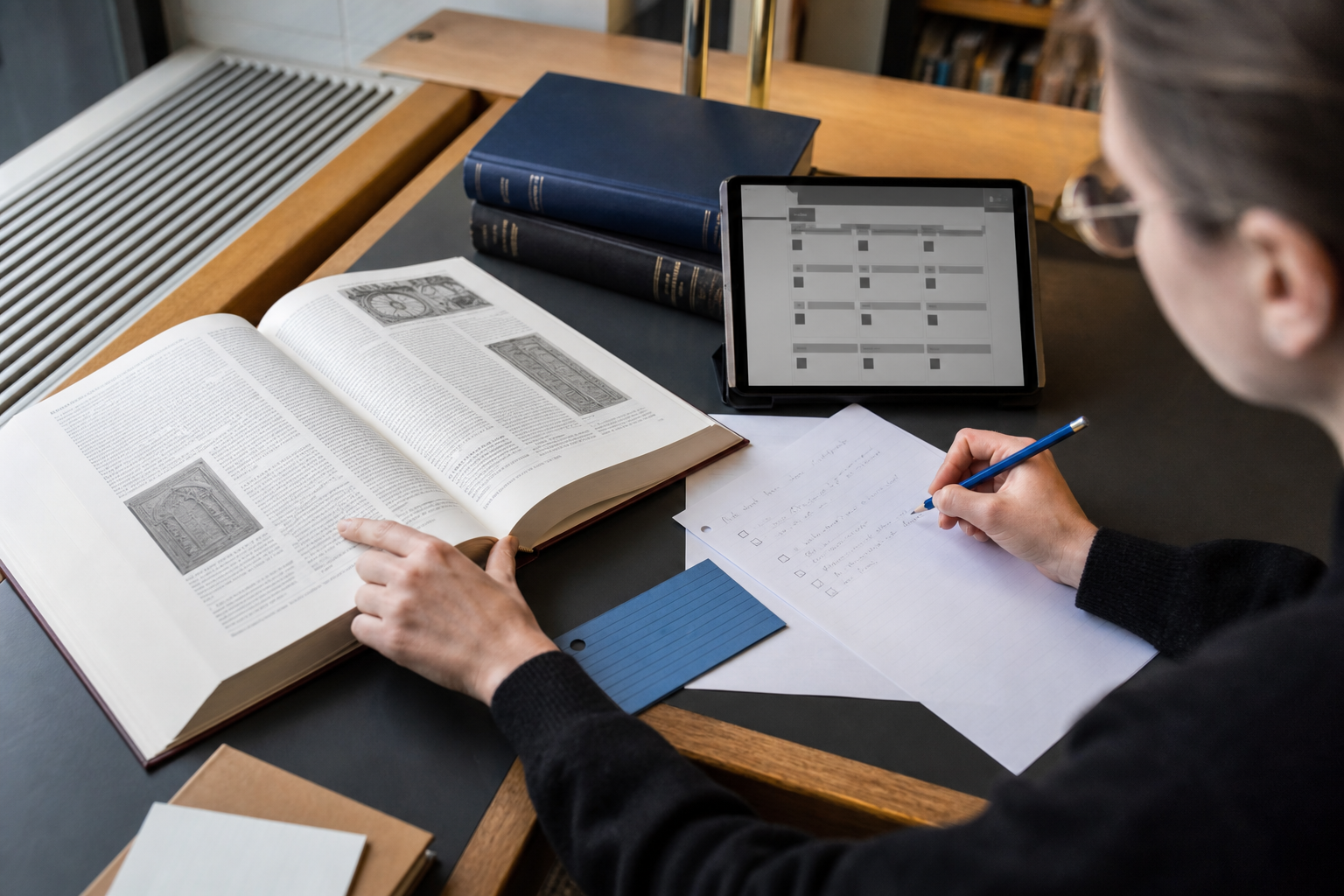 Lezer vergelijkt een naslagwerk, een catalogus en eigen notities aan een bibliotheektafel